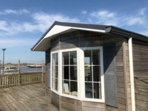 une petite maison sur une terrasse avec vue sur l'eau dans l'établissement Waterchalet number 6 Recreationpark Yn'e Lijte Grou met ligplaats boot, à Grou