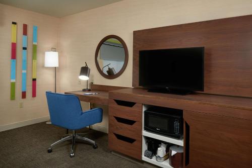a room with a desk with a television and a blue chair at Hampton Inn & Suites Phoenix-Surprise in Surprise