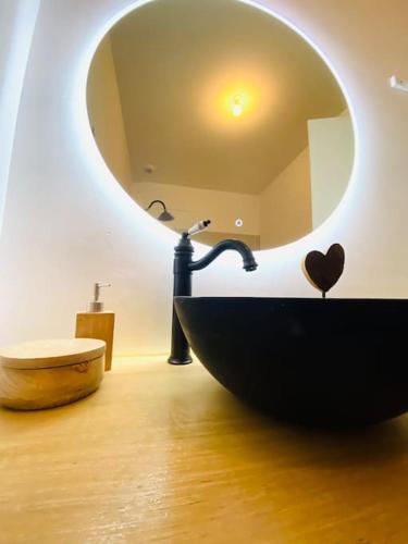 une salle de bain avec un lavabo noir et un miroir dans l'établissement Havre de paix avec jardin et clim en centre ville de Sète, à Sète