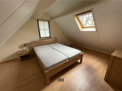een slaapkamer met een bed en twee ramen op een zolder bij Mooie 6 persoons vakantieboerderij in de Achterhoek in Eibergen