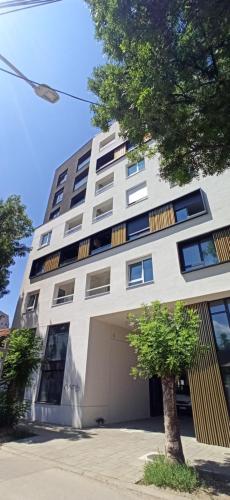 a tall white building with a tree in front of it at Lux apartment 10 center, free parking in Niš