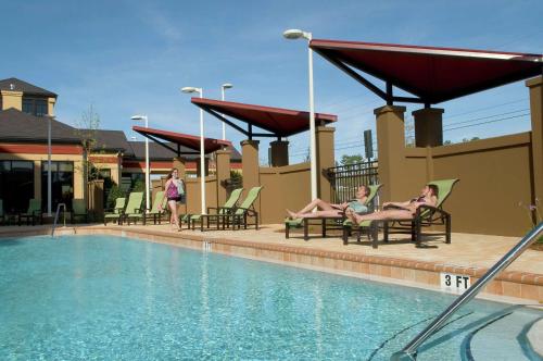 um grupo de pessoas sentadas em cadeiras ao lado de uma piscina em Hilton Garden Inn Pensacola Airport/Medical Center em Pensacola