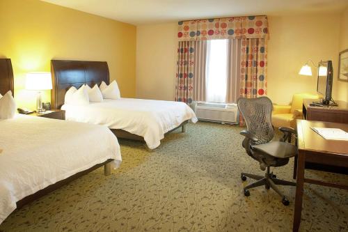 a hotel room with two beds and a desk and a chair at Hilton Garden Inn Pensacola Airport/Medical Center in Pensacola