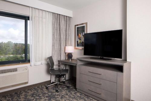 a hotel room with a desk and a flat screen tv at Embassy Suites by Hilton Portland Maine in Portland