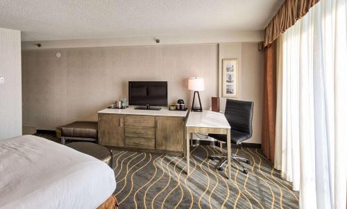 Cette chambre comprend un lit et un bureau avec une télévision. dans l'établissement DoubleTree by Hilton Portland, ME, à South Portland