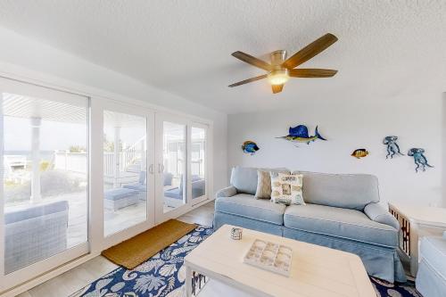 sala de estar con sofá azul y ventilador de techo en Oceanfront Oasis, en Crescent Beach