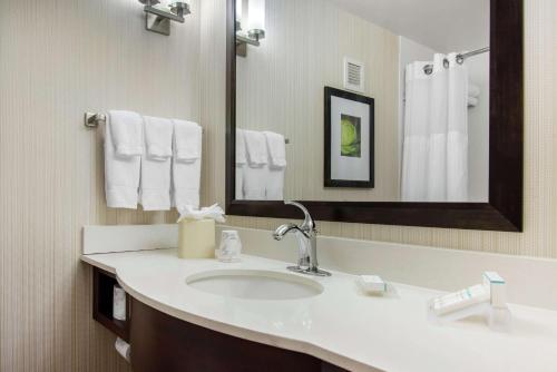 een badkamer met een wastafel, een spiegel en handdoeken bij Hilton Garden Inn Portland Airport in Portland
