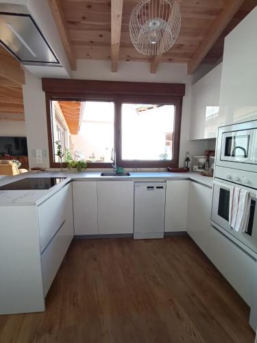a kitchen with white cabinets and a large window at CASA TITA in Campo de Villavidel