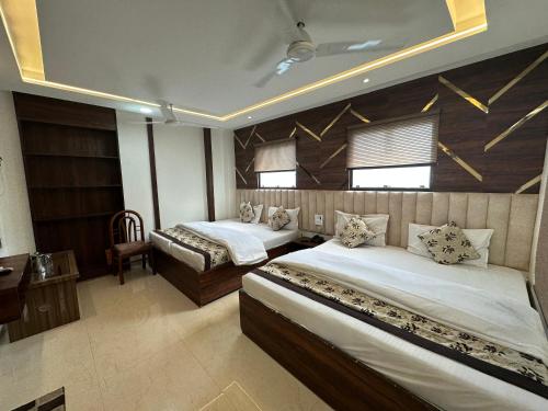 a bedroom with two beds and a desk and two windows at Hotel Seeta Since 1965 in Amritsar