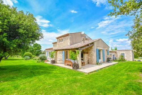 une maison en pierre avec une pelouse verte dans l'établissement Mas des Chênes Verts 5 ch avec piscine et clim, à Eygalières