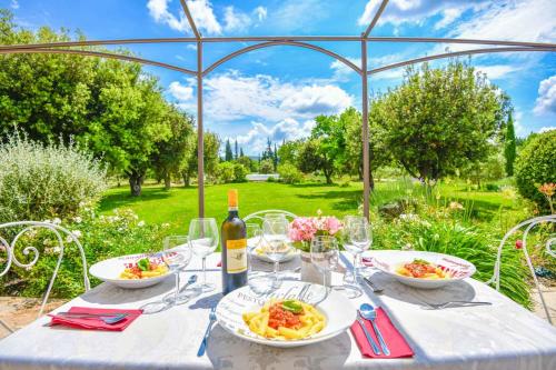 - une table avec des assiettes de nourriture et une bouteille de vin dans l'établissement Mas des Chênes Verts 5 ch avec piscine et clim, à Eygalières