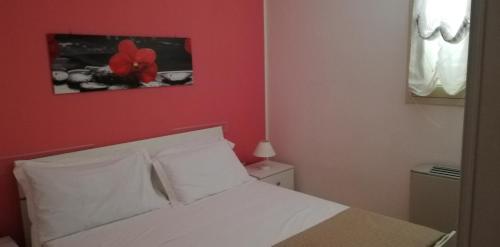 una camera con un letto bianco con una parete rossa di Mirage B&B ad Alezio