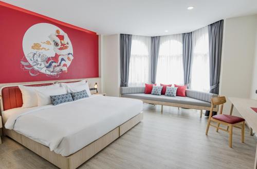 a bedroom with a large bed and a red wall at Hotel Midtown Ratsada in Phuket Town
