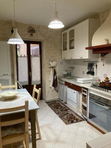 a kitchen with white cabinets and a table and a dining room at La Caponera in Riccò del Golfo di Spezia