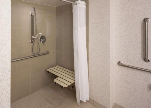 y baño con ducha a ras de suelo y banco. en Hilton Durham near Duke University en Durham