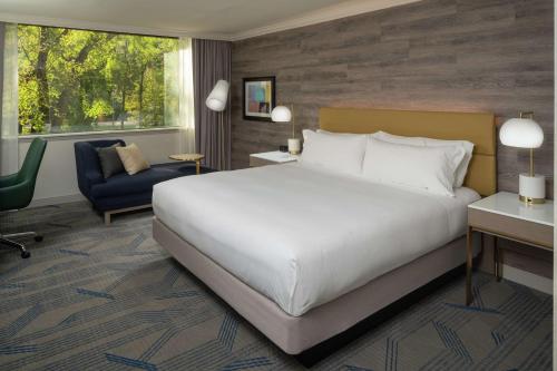 a bedroom with a large white bed and a chair at Hilton Durham near Duke University in Durham