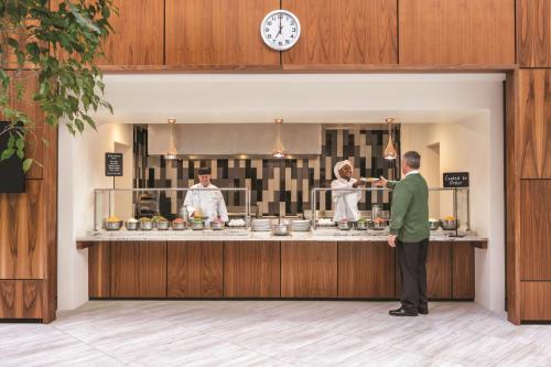 un uomo in piedi davanti a una cucina con due chef di Embassy Suites by Hilton Richmond a Richmond