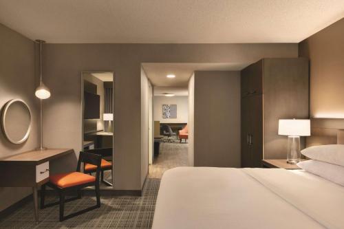 a hotel room with a bed and a desk and a bedroom at Embassy Suites by Hilton Richmond in Richmond