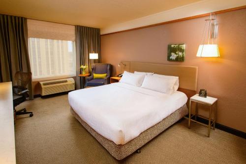 a hotel room with a large bed and a chair at Hilton Garden Inn Rochester Downtown in Rochester