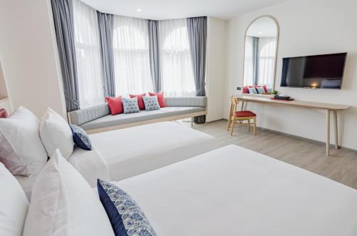 a hotel room with two beds and a tv at Hotel Midtown Ratsada in Phuket Town