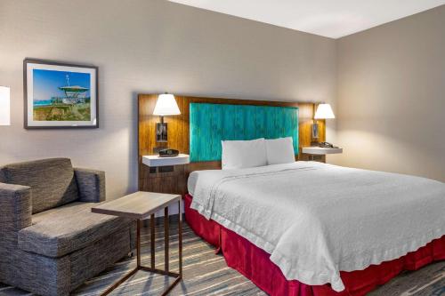 een hotelkamer met een bed en een stoel bij Hampton Inn Carlsbad North San Diego County in Carlsbad