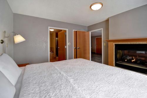 a bedroom with a white bed and a fireplace at Hampton Inn Rutland/Killington in Rutland