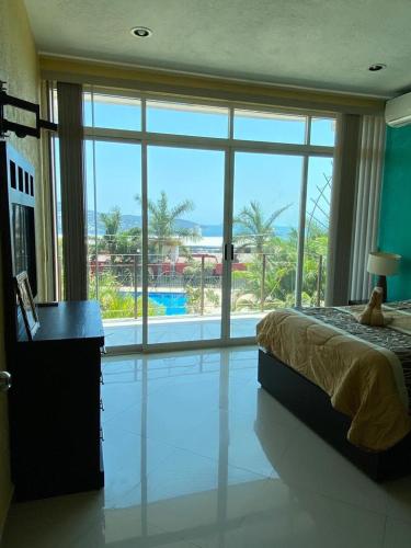 a bedroom with a bed and a large window at CONDOMINIO PALMEIRAS in Acapulco
