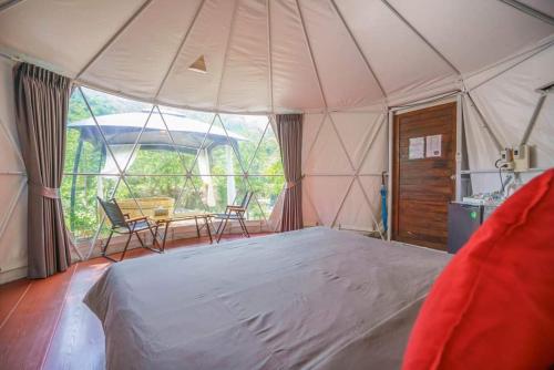 een tent met een bed en een tafel en stoelen bij ไวน์แคมป์ WineCamp โดมติดลำธาร in Ban Cha-om