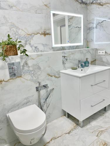 a white bathroom with a toilet and a sink at Marius Home in Chişinău