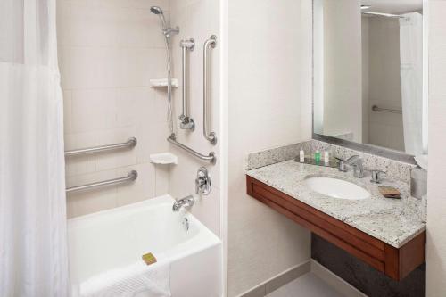 a bathroom with a sink and a tub and a mirror at DoubleTree by Hilton Hotel South Bend in South Bend