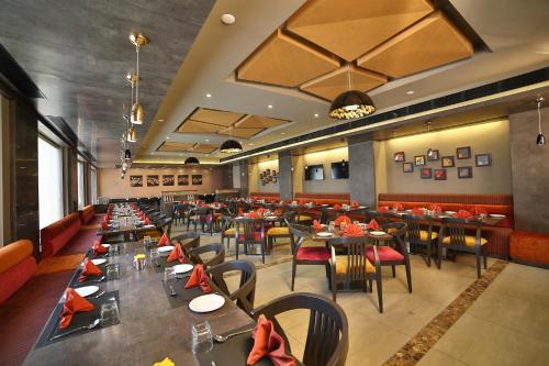 a dining room with tables and chairs in a restaurant at HOTEL G EXPRESS Formerly Known as TGB Express in Ahmedabad