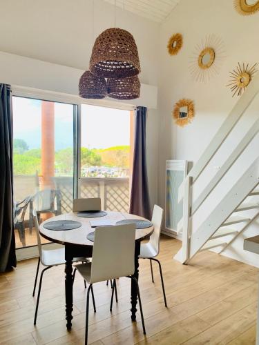 une salle à manger avec une table et des chaises et un escalier dans l'établissement - Appartement Cauris -, à Vieux-Boucau-les-Bains