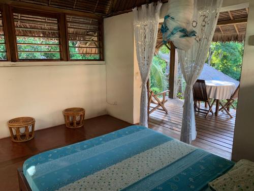 a bedroom with a bed and a balcony with a table at Les Jardins d'Ankify in Andimaka