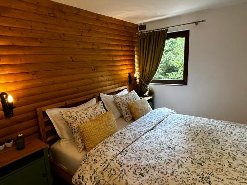 1 dormitorio con pared de madera y cama con almohadas en Mountain Chalet - Cabana la Muntele Baisorii, en Muntele Cacovei