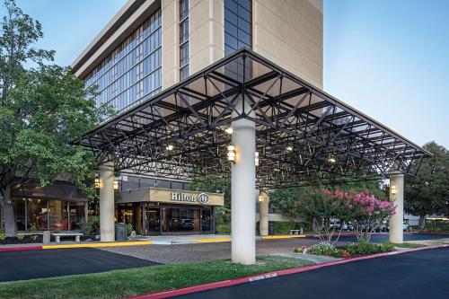 a large building with a metal canopy in front of it at Hilton Sacramento Arden West in Sacramento