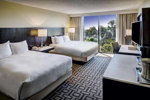 a hotel room with two beds and a television at Hilton Sacramento Arden West in Sacramento