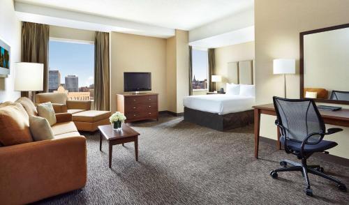 a hotel room with a bed and a couch and a desk at Hilton Saint John in Saint John