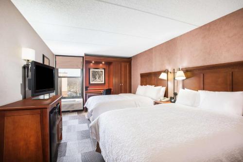 a hotel room with two beds and a flat screen tv at Hampton Inn West Springfield in West Springfield