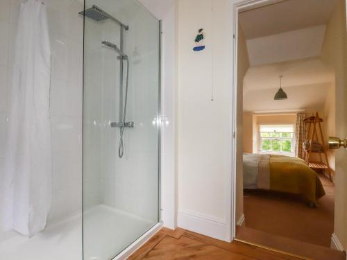a glass shower in a bathroom with a bed at Trevethen Cottage in Newquay