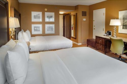 a hotel room with two beds and a desk at Hilton St. Louis Airport in Woodson Terrace