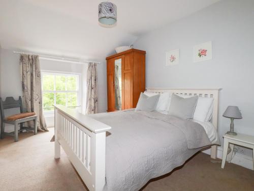 a white bedroom with a white bed and a window at Trevethen Cottage in Newquay