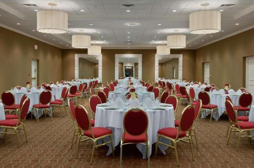 a banquet hall with white tables and red chairs at Hilton St. Louis Airport in Woodson Terrace
