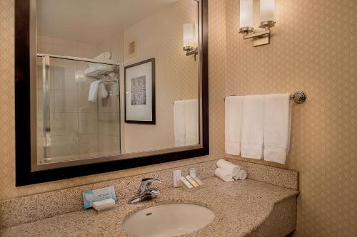 a bathroom with a sink and a mirror and towels at Hilton Garden Inn St. Louis Airport in Berkeley