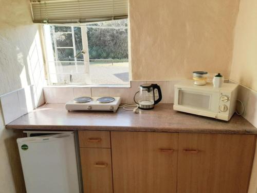 a kitchen with a counter with a microwave and a window at Rietkuil Country Cottages in Cremin