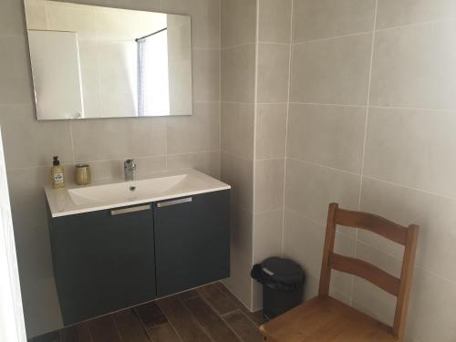 W łazience znajduje się umywalka, lustro i krzesło. w obiekcie Chambre villa florecita w mieście Labenne