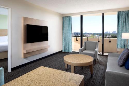 a hotel room with a television and a couch and chair at Embassy Suites by Hilton Tampa Airport Westshore in Tampa