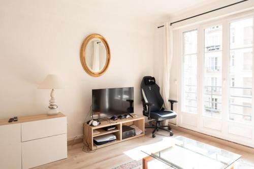 a living room with a black chair and a television at Calm and bright cocoon in Paris