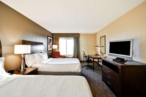 a hotel room with two beds and a flat screen tv at Hilton Garden Inn Tampa North in Tampa