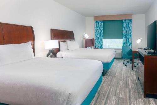 Habitación de hotel con 2 camas y escritorio en Hilton Garden Inn Tampa Riverview Brandon en Brandon