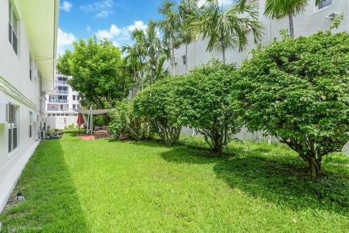 a green yard with trees in front of a building at Soleado Hotel in Fort Lauderdale